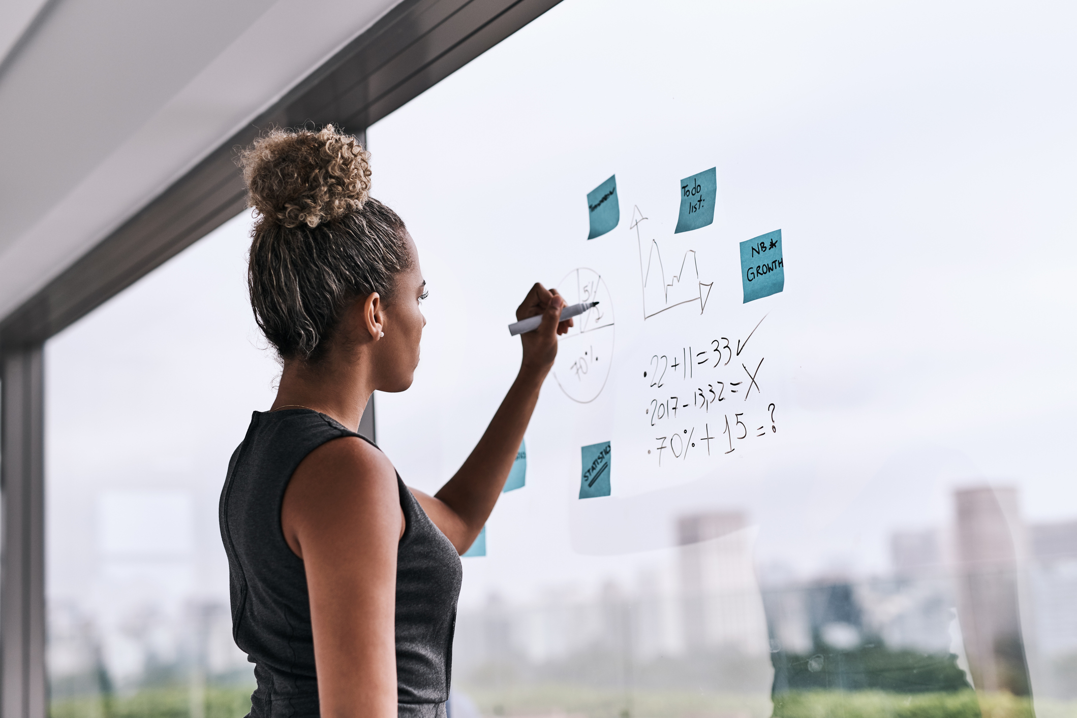 Shot of a young businesswoman writing on a glass wall in an office